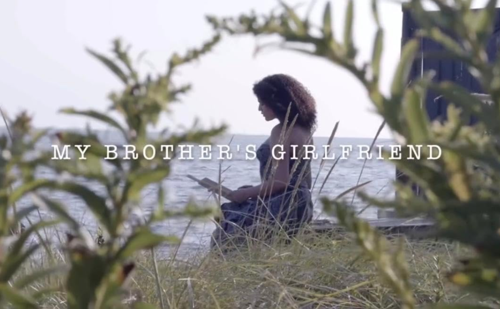 Logo/poster for My Brother's Girlfriend, showing a woman reading a book by the water.